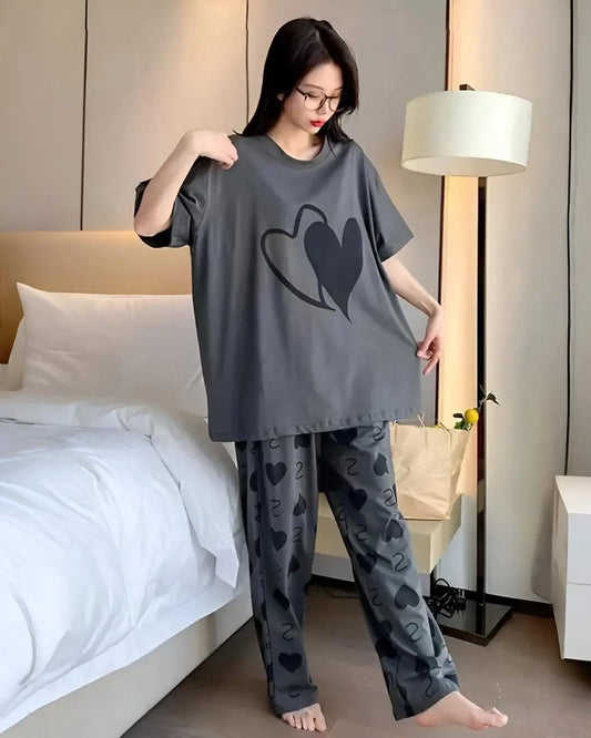 Person wearing a gray pajama set with heart patterns in a bedroom.