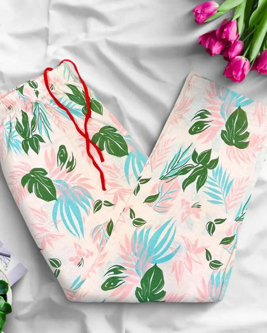 Peach-colored lounge trousers with a tropical leaf print and a red drawstring.