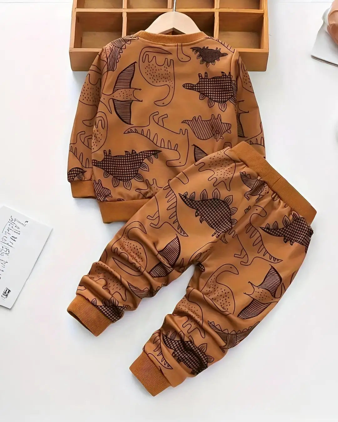 A kids' two-piece winter suit in a brown color with a repeating dinosaur print.