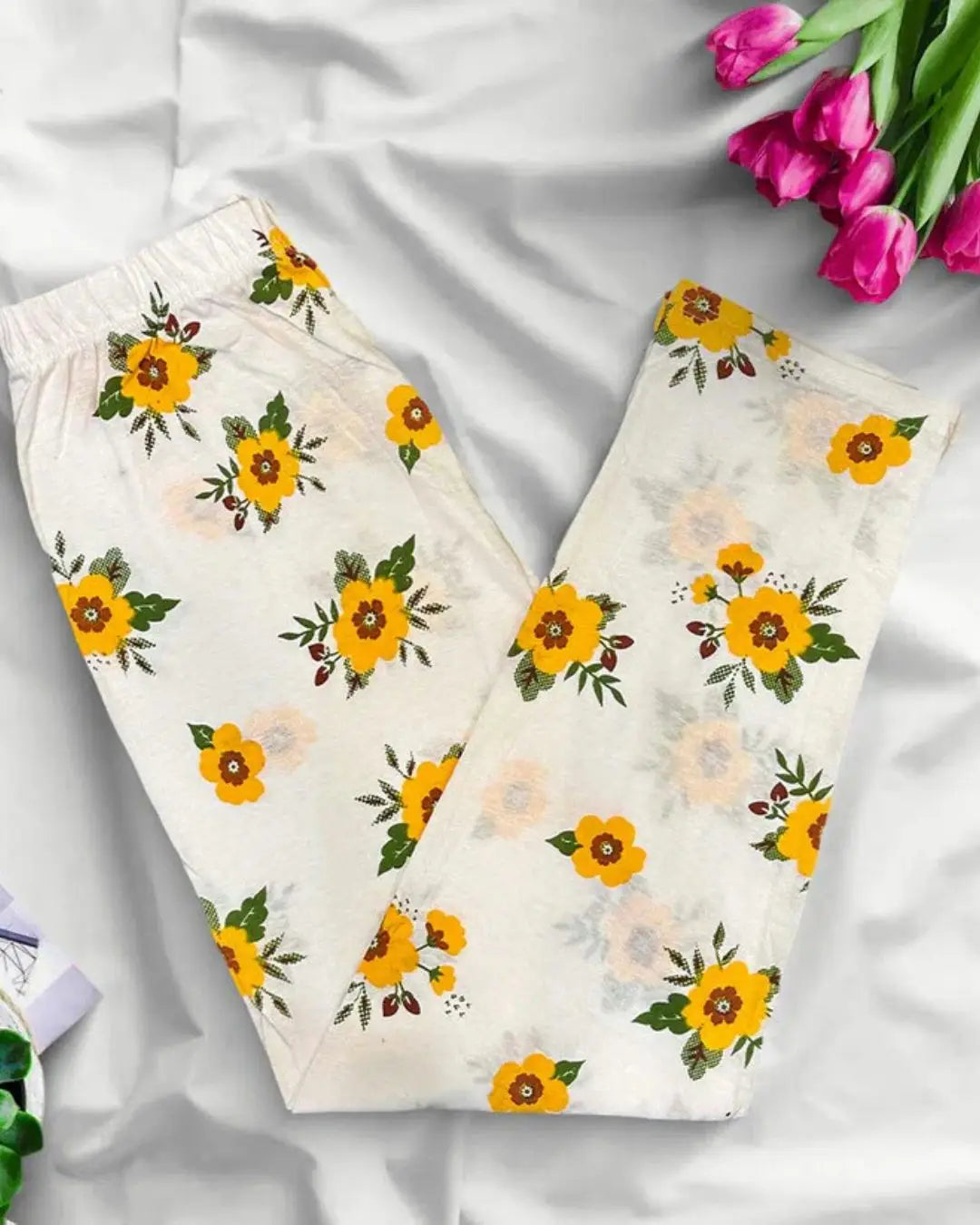 Yellow floral print trousers with a white background.