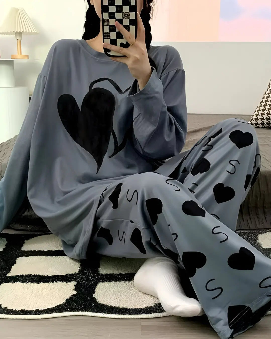 A woman wearing a full-sleeved, loose-fitting gray night suit with a dual heart print. The suit is made from a soft fabric, ideal for loungewear or sleepwear.